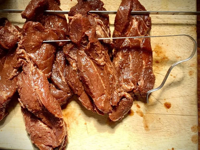 Marinated pork strips threaded onto skewers at one end