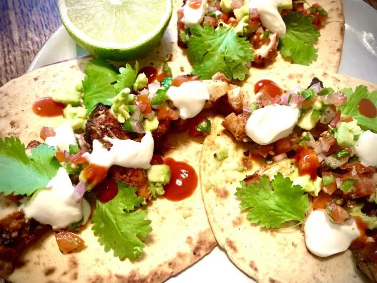 Charred chicken street tacos topped with pico de gallo, coriander, sour cream and hot sauce